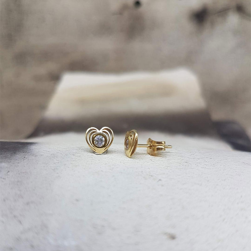Παιδικά χρυσά σκουλαρίκια Κ9 σε σχήμα καρδιάς διακοσμημένα με λευκά ζιργκόν.